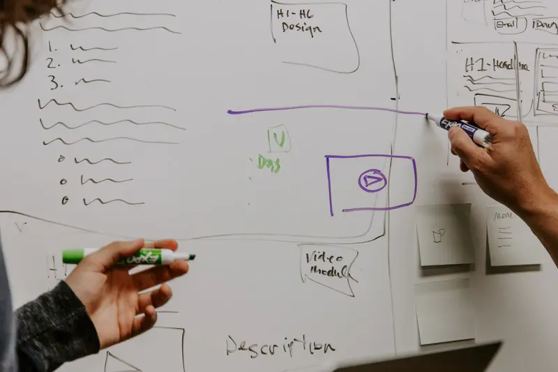 Two people sketching an application flow on a whiteboard